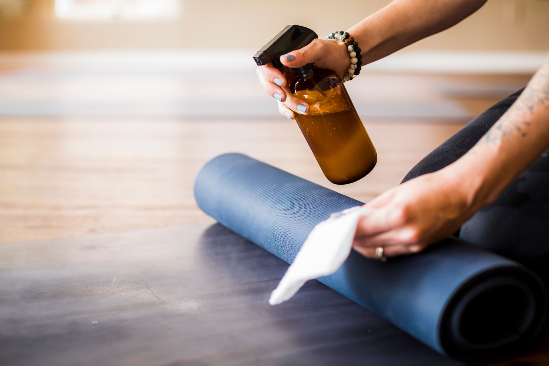 Woman cleaning yoga mat with sanitizer.